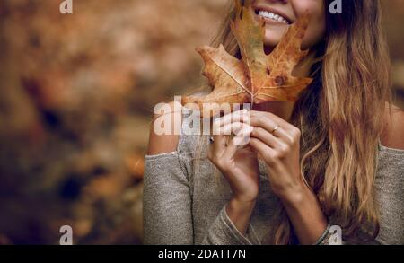 Verbunden mit der Natur schöne junge Modell posiert im Herbstlichen Park. Bedeckende Fläche mit trockenem Ahornblatt. Schönheit der Herbstsaison. Stockfoto