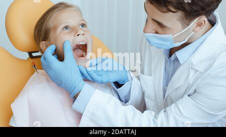 Hände von unkenntlich pädiatrischen Zahnarzt machen Untersuchung Verfahren für Lächeln Nettes kleines Mädchen Stockfoto