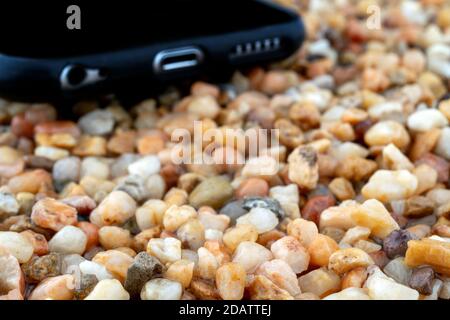 Das Smartphone liegt auf dem gelben Sand. Moderne Technologien. Stockfoto