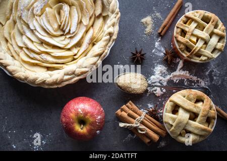 Apfelkuchen. Desserttörtchen auf einem Tisch. Foto von oben mit verschiedenen Apfelkuchen, Kuchen und Torten, frischen Pflaumen, Äpfeln und Kürbissen. Herbstmenü-Ideen. Stockfoto