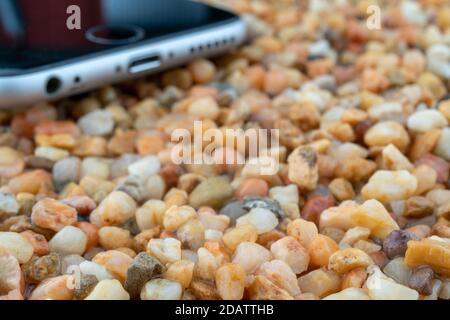 Das Smartphone liegt auf dem gelben Sand. Moderne Technologien. Stockfoto