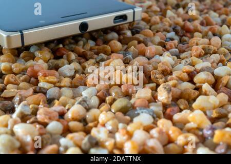 Das Smartphone liegt auf dem gelben Sand. Moderne Technologien. Stockfoto