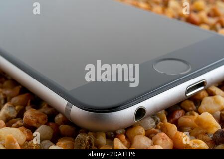 Das Smartphone liegt auf dem gelben Sand. Moderne Technologien. Stockfoto