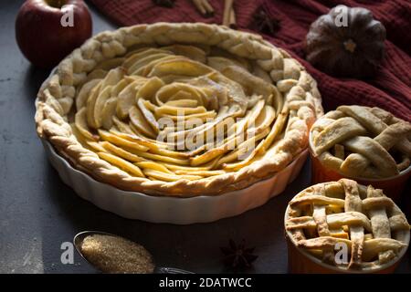 Apfelkuchen verschiedener Art auf einem Tisch mit frischem Obst, Zimtstangen und Kürbissen. Herbstmenü-Ideen. Hausgemachte Dessert Nahaufnahme Foto. Stockfoto