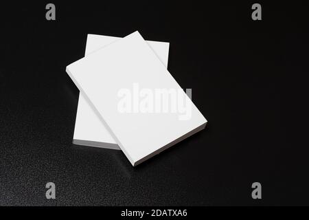 Bücher mit leerem Einband auf einem dunklen glänzenden Tisch, bearbeitbare Mock-up-Serie bereit für Ihr Design, Titelauswahl-Pfad enthalten. Stockfoto