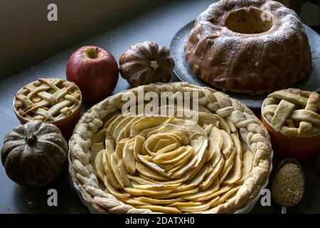 Apfelkuchen verschiedener Art auf einem Tisch mit frischem Obst, Zimtstangen und Kürbissen. Herbstmenü-Ideen. Hausgemachte Dessert Nahaufnahme Foto. Stockfoto