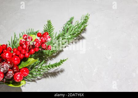 Weihnachtliche Tannenzweige, rote Eberesche mit Schnee auf grauem Hintergrund. Flach liegend, Draufsicht. Speicherplatz kopieren. Stockfoto