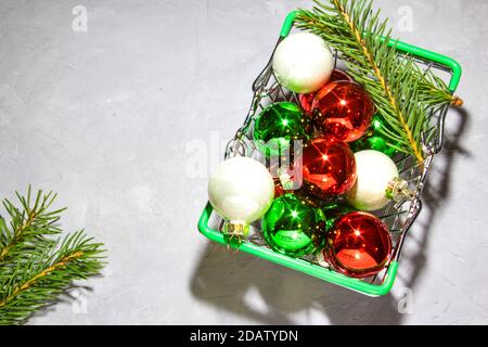 Weihnachten bunte Bälle im Warenkorb auf grauem Hintergrund. Dekorativer Rahmen. Flach liegend, Draufsicht. Speicherplatz kopieren. Stockfoto