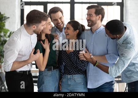 Glücklich vielfältige Millennial Freunde begrüßen indische weibliche Mate mit Erfolg Stockfoto