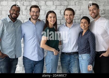 Glückliche, vielfältige junge Menschen Teamkollegen umarmen und betrachten die Kamera Stockfoto