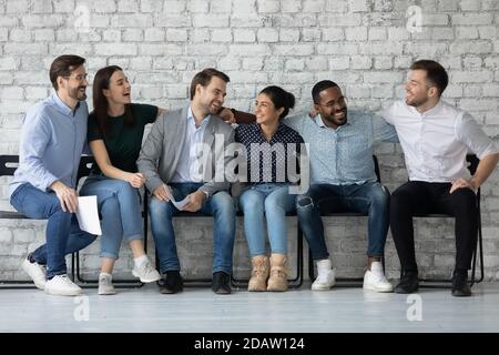 Freundliche, vielfältige Kollegen, die auf Stühlen sitzen und über Angelegenheiten reden Stockfoto