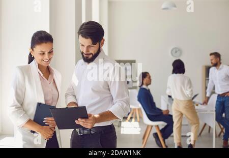 Fröhliche Kollegin, die den männlichen Kollegen in Modern berät Büroarbeitsplatz Stockfoto