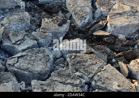 Zerbrochene Asphaltstücke auf einer Baustelle. Recycling und Wiederverwendung zerkleinerten Betonschutt, Asphalt, Baumaterial, Blöcke. Zerkleinert сoncrete Bac Stockfoto