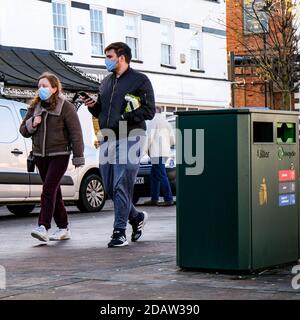 London UK, November 15 2020, Junges Paar trägt schützende Gesichtsbedeckungen Walking High Street während COVID-19 Coronavirus Lockdown Stockfoto