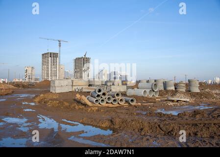 Turmdrehkrane arbeiten auf der Baustelle auf blauem Himmel Hintergrund. Verlegung von Betonschächten und Abflussrohren für das Regenwassersystem. Regenwasser aufbauen Stockfoto