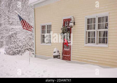 Ein Weihnachtskranz hängt an der Eingangstür eines Altes Haus nach einem Schneesturm Stockfoto