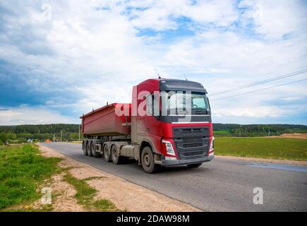 LKW mit Kipper Sattelauflieger transportierte Sand aus dem Steinbruch auf der Fahrt entlang der Autobahn. Stockfoto