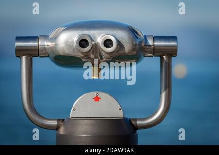 Nahaufnahme eines metallischen Münzfernglases für Touristen vor verschwommenem Hintergrund, Meer und Himmel Stockfoto