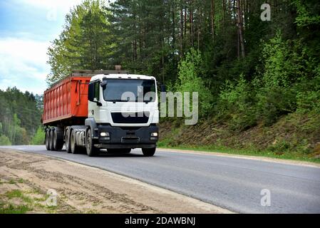 LKW mit Kipper Sattelauflieger transportierte Sand aus dem Steinbruch auf der Fahrt entlang der Autobahn. Stockfoto