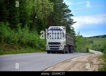 LKW mit Kipper Sattelauflieger transportierte Sand aus dem Steinbruch auf der Fahrt entlang der Autobahn. Stockfoto