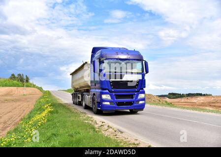 LKW mit Kipper Sattelauflieger transportierte Sand aus dem Steinbruch auf der Fahrt entlang der Autobahn. Stockfoto