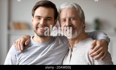 Kopf erschossen Porträt lächelnden jungen Mann mit reifen Vater umarmt Stockfoto