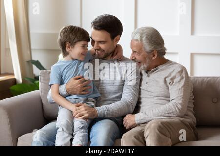 Glückliche drei Generationen von Männern umarmen, sitzen auf gemütliche Couch Stockfoto