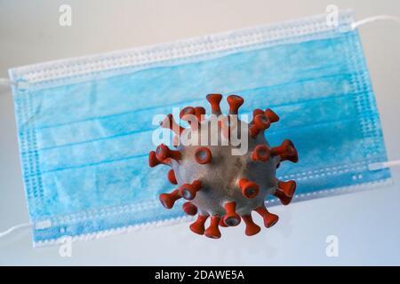 Leipzig, Deutschland. November 2020. Ein Modell eines Coronavirus liegt über einem Mund-Nase-Deckel. Quelle: Peter Endig/dpa-Zentralbild/ZB/dpa/Alamy Live News Stockfoto