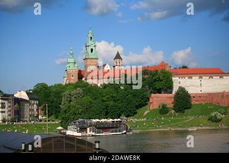 Radfahrer fahren auf der Weichselufer Straße. Im Hintergrund die Kathedrale und der Wawel Royal Castle Komplex auf Wawel Hill in Krakau Stockfoto