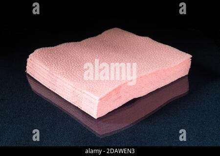 Die Rose Papierservietten auf schwarzem Hintergrund. Hygienisches Handtuch auf Glastisch mit Reflexion Stockfoto
