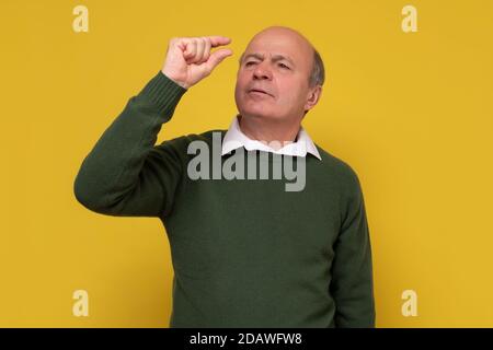 Enttäuschter älterer Mann, der nur eine kleine Länge zeigt Stockfoto