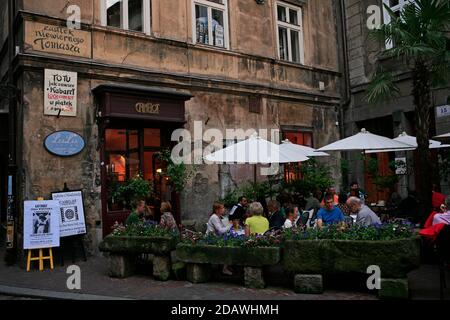 Eine Kundin an einem beleuchteten Fenstertisch, fotografiert von außen im Cafe Camelot, einem bekannten Krakauer Café-Restaurant in der Krakauer Altstadt. Stockfoto