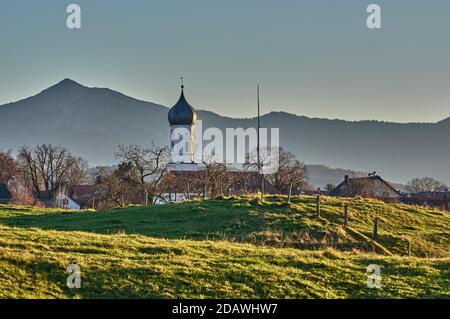 Glockenturm auf grünen Hügeln in den alpen bei Sonnenuntergang. Kirche vor einer Berg Silhouette während des Sonnenuntergangs. Kirche auf grünen Hügeln in den Bergen du Stockfoto