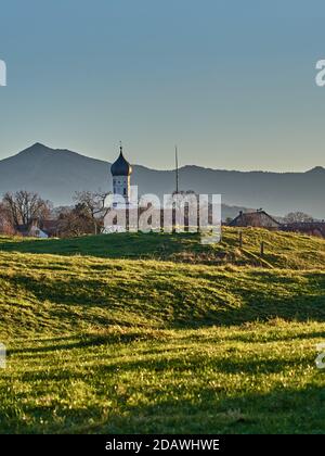 Glockenturm auf grünen Hügeln in den alpen bei Sonnenuntergang. Kirche vor einer Berg Silhouette während des Sonnenuntergangs. Kirche auf grünen Hügeln in den Bergen du Stockfoto