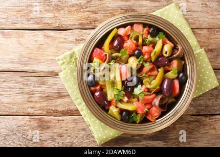 Köstlicher Salat aus Tomaten und grünen Paprika Chlada felfel mit Sardellen und Oliven in einer Schüssel auf dem Tisch. Horizontale Ansicht von oben Stockfoto