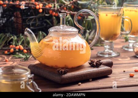 Schöne Glas Teekanne mit Sanddorntee. Heiße Getränke im Winter Stockfoto