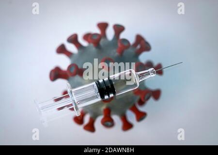 Leipzig, Deutschland. November 2020. ABBILDUNG: Eine Impfspritze liegt über einem Modell eines Coronavirus. Quelle: Peter Endig/dpa-Zentralbild/ZB/dpa/Alamy Live News Stockfoto