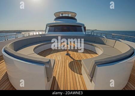 Teak Bugdeck einer großen Luxus-Motoryacht mit Stühle, Couchtisch und tropischer Meerblick im Hintergrund Stockfoto