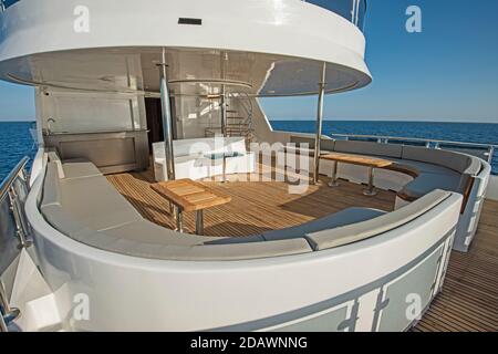 Teak Heck Holzdeck einer großen Luxus-Motoryacht Mit Sesseln, Schlafsofa und tropischem Meerblick im Hintergrund Stockfoto