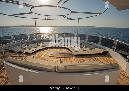 Teak Heckdeck einer großen Luxus-Motoryacht mit Liegen Stühle Sofa Tisch und tropischen Meerblick Hintergrund Stockfoto