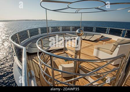 Teak Heckdeck einer großen Luxus-Motoryacht mit Sonnenliegen Stühle Sofa und tropischer Meerblick Hintergrund Stockfoto