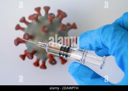 Leipzig, Deutschland. November 2020. ABBILDUNG: Eine Impfspritze wird über ein Modell eines Coronavirus gehalten. Quelle: Peter Endig/dpa-Zentralbild/ZB/dpa/Alamy Live News Stockfoto