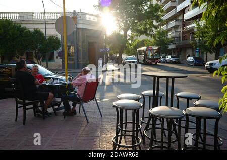 Cordoba, Argentinien - Januar, 2020: Drei Männer trinken Kaffee im Café draußen auf der Straße bei Sonnenuntergang. Stockfoto