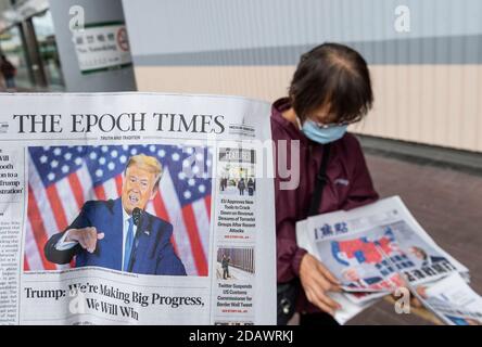Eine Frau verteilt die chinesischen und englischsprachigen Zeitungen mit dem aktuellen US-Präsidenten Donald J. Trump auf der Titelseite in Hongkong. Stockfoto
