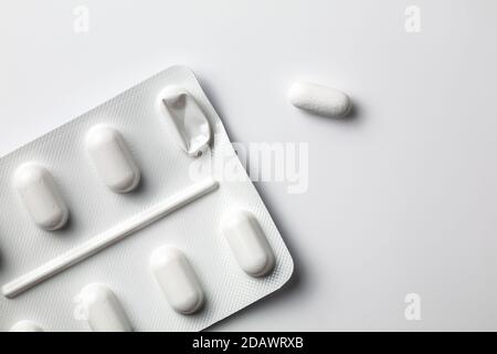 Angewinkelte Blisterpackung mit einer auf isolierte weiße Oberfläche gepressten Pille. Medicine Pillen verwendeten Medikamente einfach Stockfoto