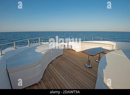 Teak Bugdeck einer großen Luxus-Motoryacht mit Stühle, Couchtisch und tropischer Meerblick im Hintergrund Stockfoto