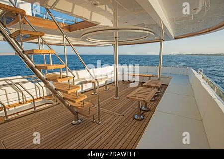 Teak Heck Holzdeck einer großen Luxus-Motoryacht Mit Sesseln, Schlafsofa und tropischem Meerblick im Hintergrund Stockfoto