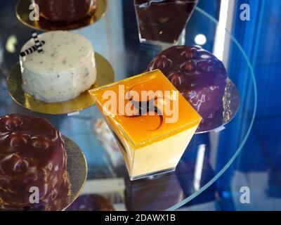 Verschiedene süße Desserts stehen auf einer runden Glasvitrine in Ein Café Stockfoto