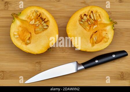 Draufsicht auf zwei Hälften Kürbis auf Holzschnitt Brett neben Küchenmesser Stockfoto