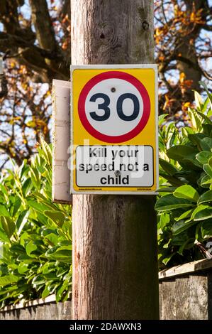 Straßenschild warnt vor 30 mph Geschwindigkeitsbegrenzung mit Schild mit der Aufschrift Kill your Speed not a child. Stockfoto